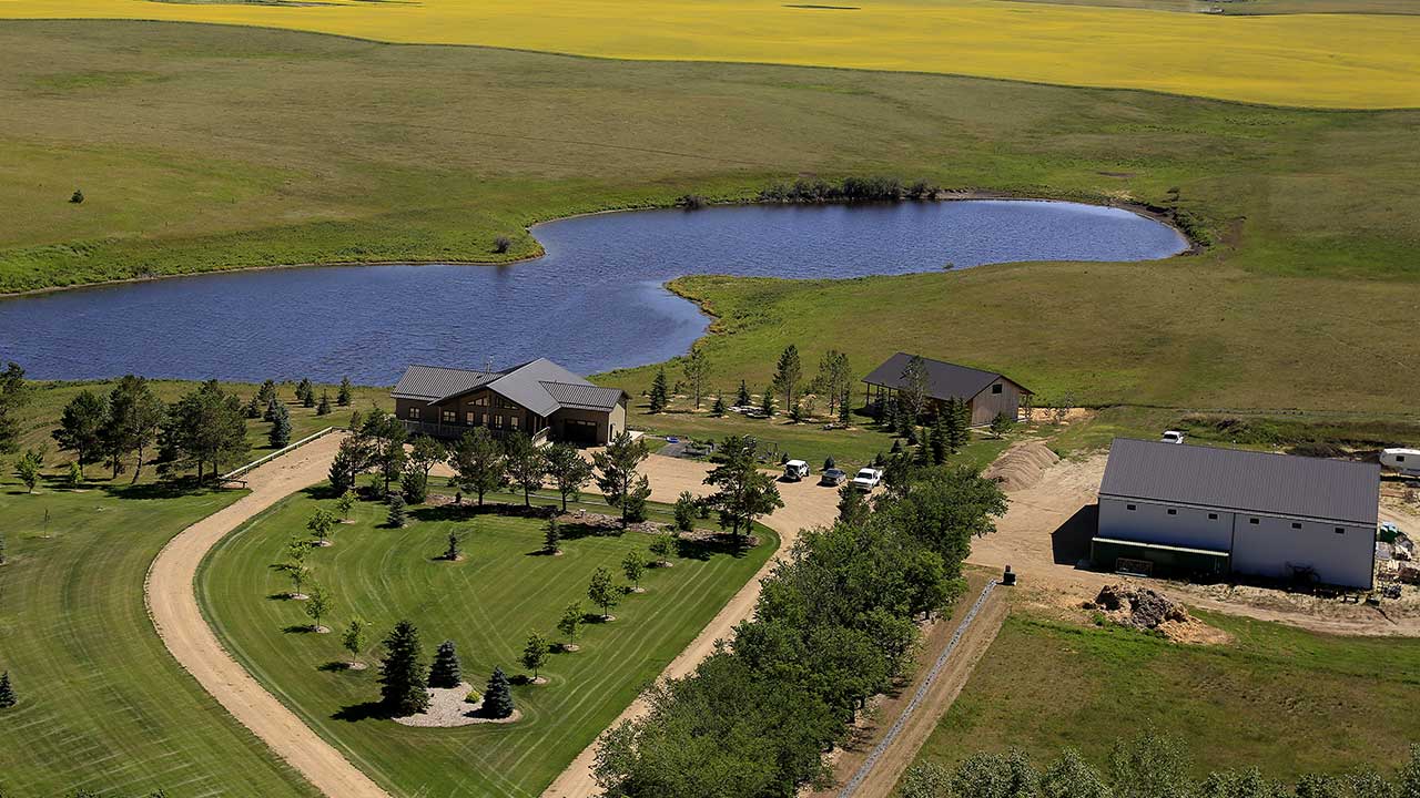 fully landscaped acreage in saskatchewan with grass, trees and buildings